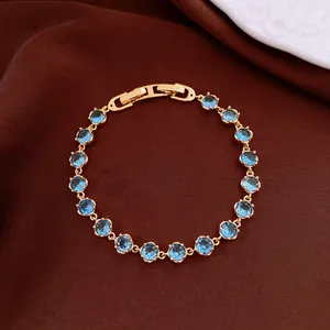 Detailaufnahme des 18k vergoldeten Armbands mit runden blauen Zirkonia auf brauner Seide.