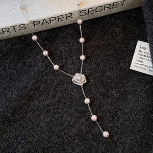 Detail view of an elegant camellia flower pendant pearl necklace with sparkling zircon accents