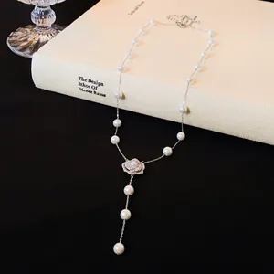 Detail view of the elegant zircon camellia pendant and pearls on a textured book.