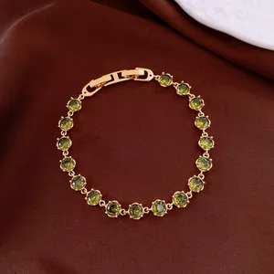 Detailansicht eines 18k vergoldeten Armbands mit runden grünen Zirkonia-Steinen.