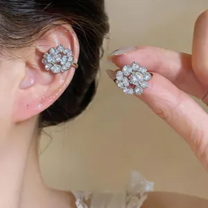 Detailed view of elegant silver zircon flower ear cuff worn on ear and held by hand.