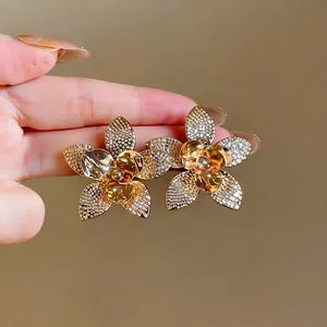 Eleganti orecchini a lobo a forma di fiore dorato con petali testurizzati e micro strass