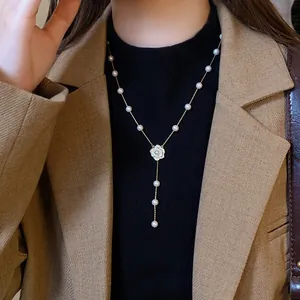 Close-up of pearl necklace with zircon camellia pendant on a model wearing a blazer