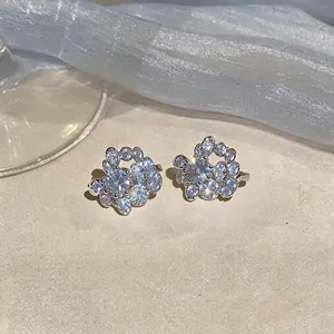 Close-up detail of circular zircon ear clips with sparkling stones in a French luxury style