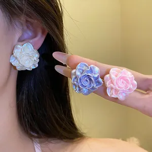 Detail view of pearlescent resin flower stud earrings in white, purple, and pink colors.