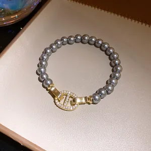 Detailansicht eines eleganten grauen Perlenarmbands mit einem goldglänzenden Schmuckelement