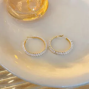 Elegante goldene Creolen mit klaren Glasperlen in einer detaillierten Makroansicht.