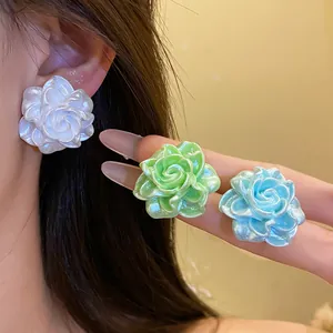 Detail of colorful resin rose earrings with pearl-like luster in white, green, and blue.