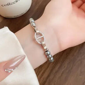 Nahaufnahme eines grauen Perlenarmbands mit einem funkelnden Schweinenasen-Glied-Detail.
