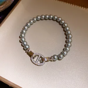 Detailansicht eines grauen Perlenarmbands mit glitzerndem Schweinenasen-Verschluss