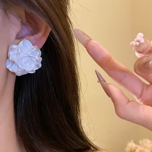 Close-up detail of a delicate white resin rose flower stud earring, elegant jewelry.
