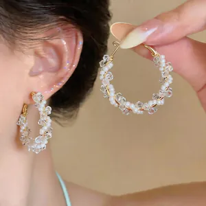 Elegante goldfarbene Creolen mit weißen Perlen und klaren facettierten Glasperlen.