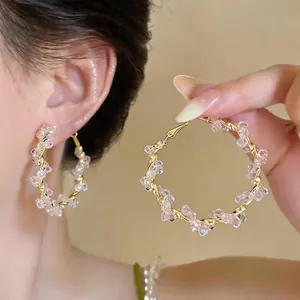 Nahaufnahme eleganter rosa Glasperlen-Creolen mit gedrehtem Golddrahtrahmen für Damen.