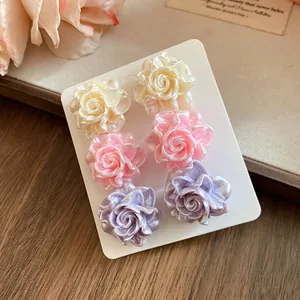 Detail shot of pearlescent resin rose stud earrings in pastel pink, purple and cream.