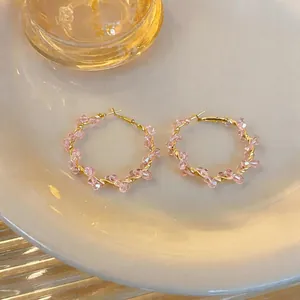 Detailreiche Makro-Aufnahme von rosa Perlenohrringen mit goldenem Draht auf Keramikteller