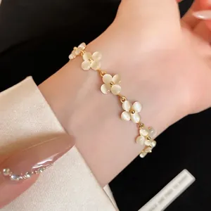 Elegant French style cat's eye stone flower bracelet with gold chain worn on female wrist