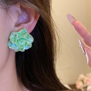 Close-up of a light green resin rose earring worn on the ear, sweet floral style