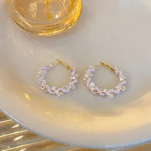 Detailansicht der handgefertigten Creolen mit rosa und klaren Glasperlen auf dem Teller