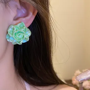 Close-up of elegant mint green resin rose stud earring on model's ear