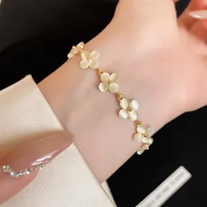 Close-up of a French style flower bracelet with white cat-eye stones on a gold chain