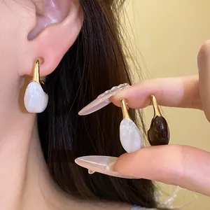 Close-up of vintage resin C-shape pendant earrings in white and dark brown marble finishes