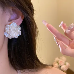 Close-up of white resin flower stud earring with delicate petals on a model's ear