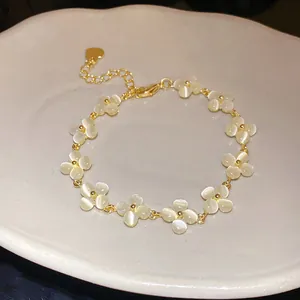 Close-up detail of a gold-plated flower bracelet featuring white cat's eye stone petals