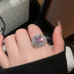 Macro primo piano di un lussuoso anello a fiore in zircone rosa scintillante su una mano
