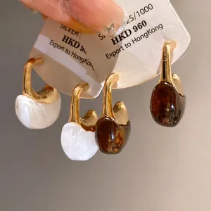 Detail view of vintage C-shaped resin hoop earrings with silver needles and glossy finish