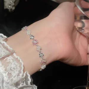Dettaglio di un bracciale a fiori di lusso con zirconi rosa e perle scintillanti.