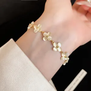Detailed close-up of a French style cat's eye stone flower bracelet on a female wrist