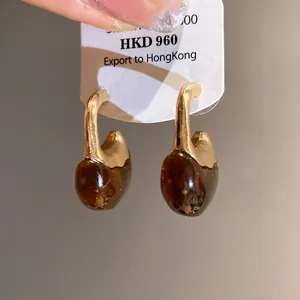 Detailed view of vintage C-shape drop earrings with amber resin and gold-tone metal finish.