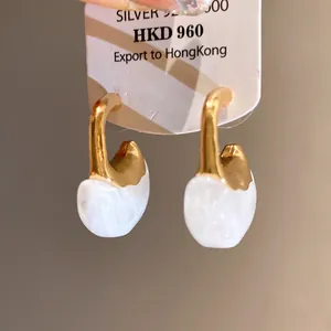 Detail of elegant resin C-shape drop earrings with gold-tone finish and marble pattern