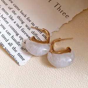 Macro view of vintage C-shaped resin earrings with elegant gold-tone metal accents