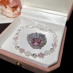 Dettaglio di un set bracciale e anello con fiori in zircone rosa in una scatola regalo