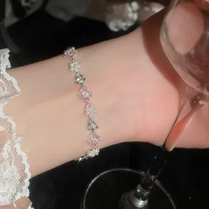 Dettaglio del bracciale floreale con zirconi e perle sul polso con elegante pizzo