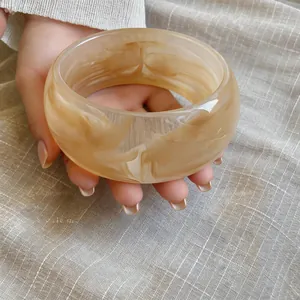 Vista macro de brazalete ancho de acrílico con elegante patrón jaspeado beige