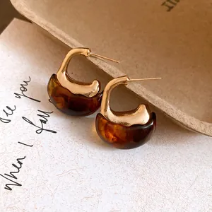 Close-up detail of elegant vintage resin C-shaped hoop earrings with gold metal accents