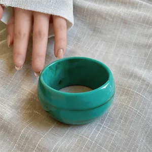 Primer plano de un grueso brazalete de acrílico turquesa jaspeado sobre tela de fondo texturizada