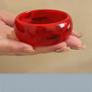 Detalle de un brazalete ancho de acrílico con motivos jaspeados en rojo y negro