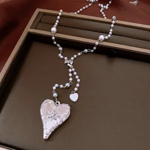 Detailed view of silver heart pendant and pearls on an adjustable necklace.