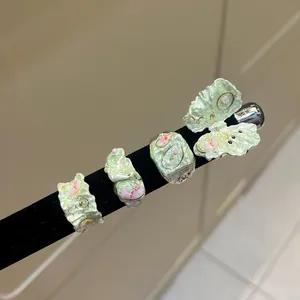 Detailed macro view of four light green enamel flower rings with sweet butterfly designs