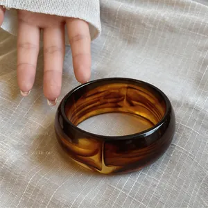 Detalle de primer plano de brazalete ancho de acrílico jaspeado con diseño de ámbar