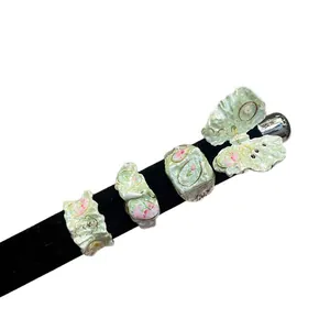 A collection of fresh green enamel floral and butterfly rings displayed on black velvet