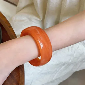 Vista detallada de un brazalete ancho redondo de acrílico vintage con veteado mármol naranja
