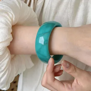 Vista detallada de un brazalete ancho de acrílico turquesa vintage puesto en la muñeca