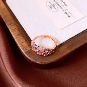 Elegant rose gold flower ring with purple zircons on wooden tray background