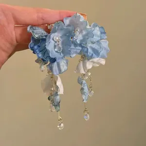Dettaglio macro di orecchini a fiore in tessuto blu con eleganti nappe di cristallo