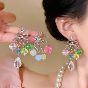 Dettaglio orecchini nappine con perle di vetro colorate e finitura argento stile.