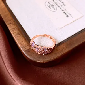 Macro view of a rose gold ring featuring irregular purple and clear zircon stones.